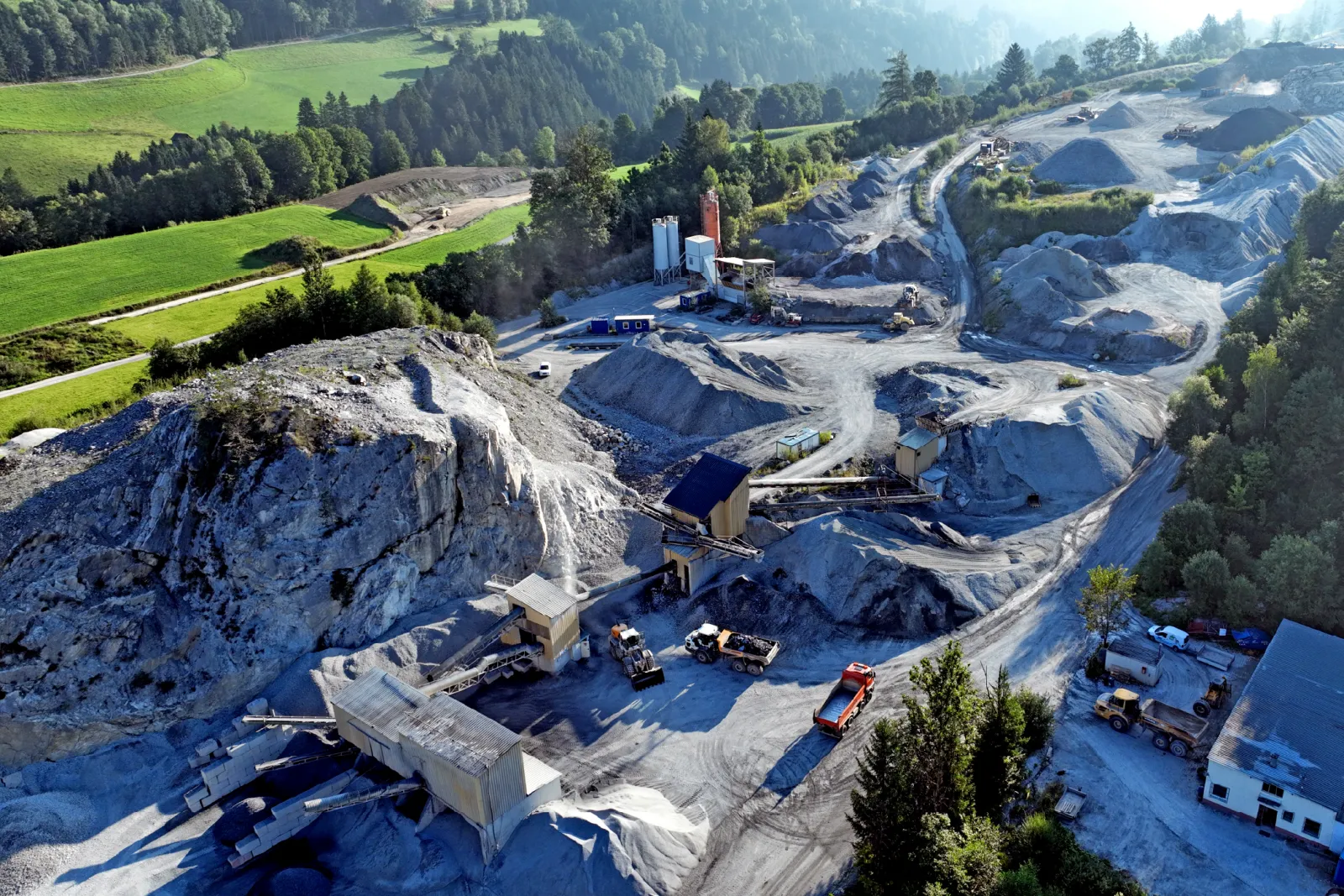 Blick von oben auf Abbauwand und Maschinen im Steinbruch